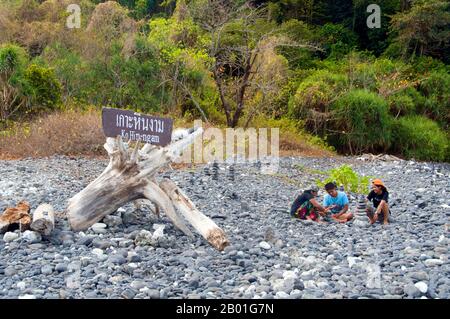 Thailand: Besucher am Kieselstrand, Ko hin Ngam, Ko Tarutao Marine National Park. Ko hin Ngam bedeutet auf Thai „Insel der schönen Steine“, und der kleine Strand ist mit glatten schwarzen Steinen in verschiedenen Formen bedeckt und mit charakteristischen Mustern bedeckt. Der Marine-Nationalpark Ko Tarutao besteht aus 51 Inseln in zwei Hauptgruppen, die über die Andamanensee im südlichsten Thailand verstreut sind. Nur sieben der Inseln haben jede Größe, einschließlich Ko Tarutao im Osten und Ko Adang-Ko Rawi im Westen. Nur 5 Meilen (8km km) südlich liegt die Meeresgrenze mit Malaysias gefeiertem Langkawi-Archipel. Stockfoto