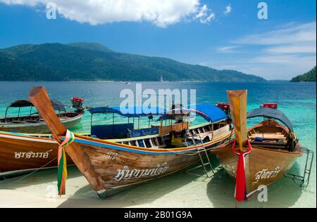 Thailand: Boote am Strand mit Ko Adang im Hintergrund, Ko Rawi, Ko Tarutao Marine National Park. Ko Rawi ist die zweitgrößte Insel der Adang-Rawi Gruppe, die selbst Teil des Ko Tarutao Marine National Park ist. Es hat eine Fläche von etwa 29 Quadratkilometern (11,5 Quadratmeilen) und liegt nur 10km km (6 Meilen) westlich von Ko Adang. Der Marine-Nationalpark Ko Tarutao besteht aus 51 Inseln in zwei Hauptgruppen, die über die Andamanensee im südlichsten Thailand verstreut sind. Nur sieben der Inseln haben jede Größe, einschließlich Ko Tarutao im Osten und Ko Adang-Ko Rawi im Westen. Stockfoto