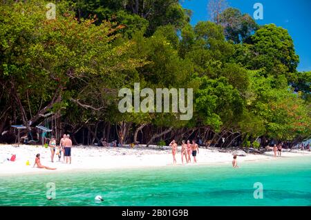 Thailand: Eine Reisegruppe entspannt sich am Strand von Ko Rawi, Ko Tarutao Marine National Park. Ko Rawi ist die zweitgrößte Insel der Adang-Rawi Gruppe, die selbst Teil des Ko Tarutao Marine National Park ist. Es hat eine Fläche von etwa 29 Quadratkilometern (11,5 Quadratmeilen) und liegt nur 10km km (6 Meilen) westlich von Ko Adang. Der Marine-Nationalpark Ko Tarutao besteht aus 51 Inseln in zwei Hauptgruppen, die über die Andamanensee im südlichsten Thailand verstreut sind. Nur sieben der Inseln haben jede Größe, einschließlich Ko Tarutao im Osten und Ko Adang-Ko Rawi im Westen. Stockfoto