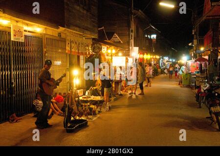 Thailand: Straßenmusiker, der am späten Abend Einkäufer auf der Chai Kong Road, Chiang Khan, Provinz Loei unterhält. Die Provinz Loei (Thai: เลย) befindet sich im oberen Nordosten Thailands. Die benachbarten Provinzen sind (von Osten nach rechts) Nong Khai, Udon Thani, Nongbua Lamphu, Khon Kaen, Phetchabun, Phitsanulok. Im Norden grenzt sie an die Provinzen Xaignabouli und Vientiane in Laos. Die Provinz ist von niedrigen Bergen bedeckt, während die Hauptstadt Loei in einem fruchtbaren Becken liegt. Der Fluss Loei, der durch die Provinz fließt, ist ein Nebenfluss des Mekong. Stockfoto