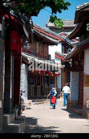 China: Naxi-Frau in einer Straße in der Altstadt von Lijiang, Provinz Yunnan. Die Naxi oder Nakhi sind eine ethnische Gruppe, die in den Ausläufern des Himalaya im Nordwesten der Provinz Yunnan und im Südwesten der Provinz Sichuan in China lebt. Man geht davon aus, dass die Naxi ursprünglich aus Tibet stammen und bis vor kurzem die Landhandelsverbindungen mit Lhasa und Indien aufrechterhalten haben. Die Naxi gehören zu den 56 ethnischen Gruppen, die von der Volksrepublik China offiziell anerkannt wurden. Die Naxi sind traditionell Anhänger der Dongba-Religion. Stockfoto