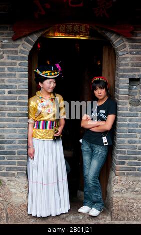 China: Mosuo-Mädchen und -Freundin vor einem Restaurant in der Altstadt von Lijiang, Provinz Yunnan. Die Mosuo (auch Moso oder Musuo), die sich selbst oft als Na bezeichnet, sind eine kleine ethnische Gruppe, die in den Provinzen Yunnan und Sichuan in der Nähe der Grenze zu Tibet lebt. Mit einer Bevölkerung von etwa 40.000 leben die meisten von ihnen in der Region Yongning und rund um den Lugu-See, hoch oben im tibetischen Himalaya. Obwohl sich die Mosuo kulturell von den Nakhi unterscheiden, sieht die chinesische Regierung sie als Mitglieder der Nakhi-Minderheit (auch bekannt als Naxi) an. Die Altstadt von Lijiang ist mehr als 800 Jahre alt. Stockfoto