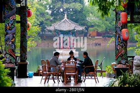 China: Kartenspielen in einem Teehaus im Black Dragon Pool Park, nördlich der Altstadt von Lijiang, Provinz Yunnan. Die Naxi oder Nakhi sind eine ethnische Gruppe, die in den Ausläufern des Himalaya im Nordwesten der Provinz Yunnan und im Südwesten der Provinz Sichuan in China lebt. Man geht davon aus, dass die Naxi ursprünglich aus Tibet stammen und bis vor kurzem die Landhandelsverbindungen mit Lhasa und Indien aufrechterhalten haben. Die Naxi gehören zu den 56 ethnischen Gruppen, die von der Volksrepublik China offiziell anerkannt wurden. Die Naxi sind traditionell Anhänger der Dongba-Religion. Stockfoto