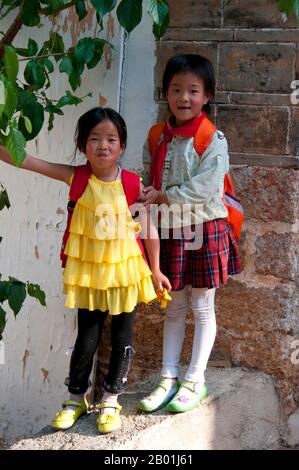 China: Schulmädchen in der Altstadt auf dem Heimweg, Altstadt von Lijiang, Provinz Yunnan. Die Naxi oder Nakhi sind eine ethnische Gruppe, die in den Ausläufern des Himalaya im Nordwesten der Provinz Yunnan und im Südwesten der Provinz Sichuan in China lebt. Man geht davon aus, dass die Naxi ursprünglich aus Tibet stammen und bis vor kurzem die Landhandelsverbindungen mit Lhasa und Indien aufrechterhalten haben. Die Naxi gehören zu den 56 ethnischen Gruppen, die von der Volksrepublik China offiziell anerkannt wurden. Die Naxi sind traditionell Anhänger der Dongba-Religion. Stockfoto