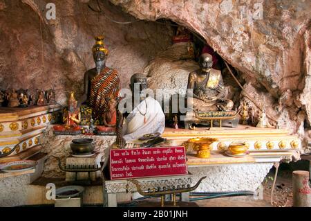 Thailand: Statuen in den Höhlen von Wat Tham Seua, Krabi Town, Krabi Province, Südthailand. Wat Tham Seua, der „Tempel der Tigerhöhle“, ist in eine Höhle in einer Kalksteinklippe gebaut. Umgeben von einzelnen Mönchsresidenzen ist dies einer der bekanntesten Waldtempel im Süden Thailands. Der Hauptviharn oder die Montagehalle erstreckt sich in eine lange, flache Kalksteinhöhle, die verschiedene düstere Erinnerungen an die Sterblichkeit als Gegengewicht zu den weltlichen Wünschen zeigt. Hinter der Höhle führt eine Marmortreppe hinauf zur „Tigerhöhle“ selbst. Stockfoto