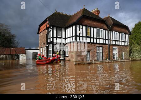 Die Mitglieder des Bergrettungsteams versuchen, einen Mann aus seinem Haus zu retten, der in Monmouth von einem starken Hochwasser umgeben ist, nach dem Sturm Dennis. Stockfoto