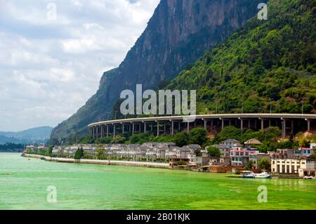 China: Highway unterhalb der Western Hills (Xishan), in der Nähe von Kunming, Provinz Yunnan. Der Dian Lake oder Kunming Lake ist ein großer Binnensee auf dem Yunnan-Guizhou Plateau in der Nähe von Kunming, Provinz Yunnan. Sein Spitzname ist „Sparkling Pearl Embedded in a Highland“ und er war das Modell für den Kunming-See im Sommerpalast in Peking. Es handelt sich um einen Süßwasserverwerfungssee auf 1.886,5 m (6.189 ft) über dem Meeresspiegel. Der See erstreckt sich über 298 km2 (115 km²). Er ist 39 km lang von Norden nach Süden und die durchschnittliche Tiefe beträgt 4,4 m. Er ist der achtgrößte See in China. Stockfoto