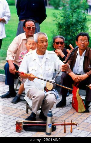 China: Ein Mann spielt einen Banhu in einem Park in Wuwei, Provinz Gansu. Die Stadt Wuwei hat eine Bevölkerung von etwa 500.000, hauptsächlich Han-Chinesen, aber mit sichtbaren Zahlen von Hui sowie Mongolen und Tibetern. Früher hieß es Liangzhou. Er dominiert das östliche Ende des Hexi-Korridors und spielt seit langem eine wichtige Rolle auf dieser wichtigen Handelsroute. WuWeis berühmtestes historisches Artefakt, das gefeierte Bronzepferd der Han-Dynastie (206 v. Chr. - 220 n. Chr.), bekannt als das fliegende Pferd von Gansu, wurde hier in einem Grab unter dem Leitai-Tempel (Leitai Si) im nördlichen Teil der Stadt entdeckt. Stockfoto