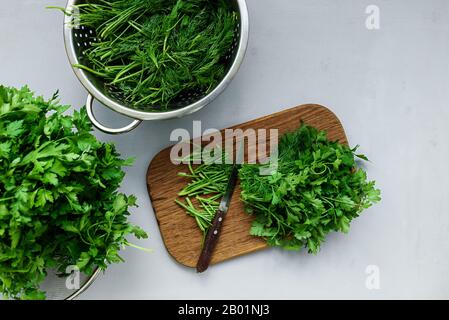 Frische grüne Petersilie und Dill oder Fenchel auf Wildschwein auf grau Holztisch gehackt. Ansicht von oben. Kopieren Sie Platz. Ernte Konzept Stockfoto