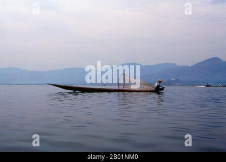Birma/Myanmar: Ein Intha-Fischer in seinem Boot auf dem Inle-See im Bundesstaat Shan. Der Inle Lake ist ein Süßwassersee in der Nyaungshwe Township im Taunggyi District des Bundesstaates Shan, Teil der Shan Hills in Myanmar (Burma). Er ist der zweitgrößte See in Myanmar mit einer geschätzten Fläche von 44,9 Quadratmeilen (116 km2) und einer der höchsten in einer Höhe von 2.900 Fuß (880 m). Die Einwohner des Inle Lake (genannt Intha), etwa 70.000, leben in vier Städten am Ufer des Sees, in zahlreichen kleinen Dörfern am Ufer des Sees und auf dem See selbst. Stockfoto