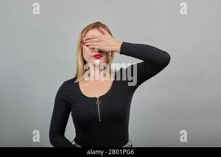 Junge Mädchen in schwarzer Jacke stilvoll Frau versteckt sich, bedeckt Gesicht mit der Hand Stockfoto