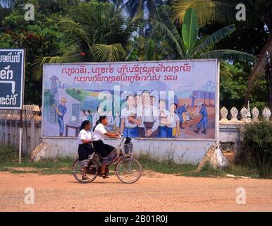 Laos: Zwei Schulmädchen fahren auf den Straßen von Vientiane vor einem sozialistisch-realistischen Bildungs- und Industrieplakat. Der sozialistische Realismus ist ein Stil realistischer Kunst, der in der Sowjetunion entwickelt wurde und in anderen kommunistischen Ländern zu einem dominierenden Stil wurde. Der sozialistische Realismus ist ein teleologisch orientierter Stil, dessen Ziel die Förderung der Ziele des Sozialismus und des Kommunismus ist. Obwohl sie damit verbunden ist, darf sie nicht mit dem sozialen Realismus verwechselt werden, einer Art von Kunst, die Themen sozialer Belange realistisch darstellt. Stockfoto