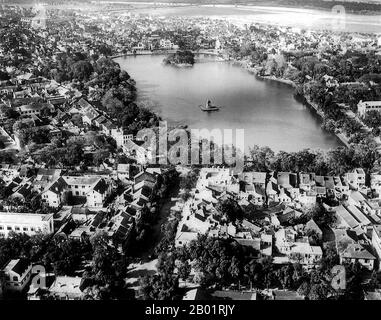 Vietnam: Luftaufnahme von Ho Hoan Kiem, dem „See des restaurierten Schwertes“, um 1940er Jahre Der Hoan Kiem See (Vietnamesisch Hồ Hoàn Kiếm, was „See des zurückgekehrten Schwerts“ bedeutet, auch bekannt als Hồ Gươm – Schwertsee) ist ein See im historischen Zentrum von Hanoi, der Hauptstadt Vietnams. Der See ist einer der landschaftlich bedeutendsten Orte der Stadt und dient als Mittelpunkt des öffentlichen Lebens. Der Legende nach überreichte Kaiser Lê Lợi ein magisches Schwert namens Himmelswille, das ihm den Sieg in seiner Revolte gegen die chinesische Ming-Dynastie zurück zum Goldenen Schildkrötengott (Kim Qui) im See brachte. Stockfoto