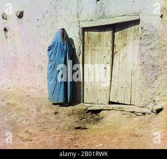 Usbekistan: "SART Woman. Samarkand. Eine Frau in Purdah, die neben einer Holztür steht. Foto von Sergej Michailowitsch Prokudin-Gorskii (31. August 1863 - 27. September 1944), ca. 1905-1915. Eine Paranja oder Paranji, auf Arabisch als „Burka“ bekannt, ist ein traditionelles zentralasiatisches Gewand für Frauen, das sie von Kopf bis Fuß umhüllt. In den 1800er Jahren mussten Frauen der Tadschiken und usbekischen Muslime Paranja tragen, wenn sie außerhalb ihres Hauses waren. Während der Sowjetunion wurden sie verboten, obwohl einige Usbeken sich gewaltsam gegen die Paranja wandten. Heutzutage tragen die meisten zentralasiatischen Frauen keine Paranja. Stockfoto