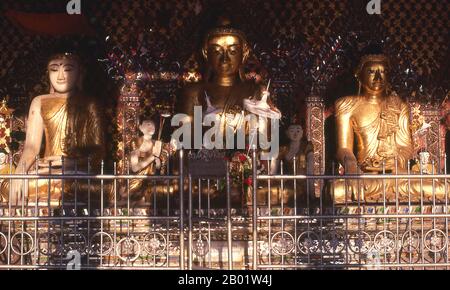 Birma/Myanmar: Buddha-Figuren in einem kleinen Schrein im Shwedagon-Pagode-Komplex, Yangon (Rangun). Die goldene Stupa der Shwedagon-Pagode erhebt sich fast 100 m (330 ft) über ihrer Lage auf dem Singuttara Hill und ist mit 8.688 massiven Goldplatten überzogen. Diese zentrale Stupa ist von mehr als 100 anderen Gebäuden umgeben, darunter kleinere Stupas und Pavillons. Die Pagode war bereits gut etabliert, als Bagan Burma im 11. Jahrhundert dominierte. Königin Shinsawbu, die im 15. Jahrhundert regierte, soll der Pagode ihre heutige Form gegeben haben. Stockfoto