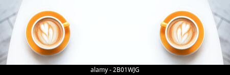 Banner aus Cappuccino mit mattem Schaum, gelbe Kaffeetasse mit Blick auf die Nahaufnahme befindet sich auf dem weißen Hintergrund. Flacher Laienstil. Stockfoto