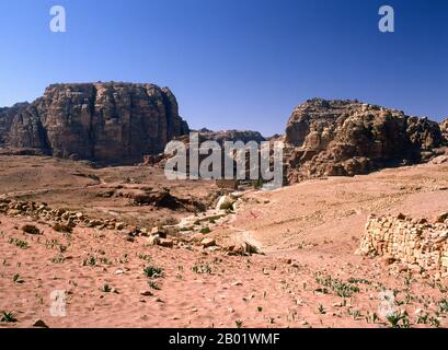 Jordanien: Blick auf den Tempel von Dushares (Qasr al-Bint) und die Kolonnade Petra. Petra wurde im 4. Jahrhundert v. Chr. von den nabatäischen Arabern als Stadt gegründet und verdankt seine Geburt und seinen Wohlstand der Tatsache, dass es der einzige Ort mit klarem und reichlich Wasser zwischen den Hidschas-Handelszentren Mekka und Medina und Palästina war. Direkt in die nubischen Sandsteinkämme der südjordanischen Wüste gehauen, scheint es wahrscheinlich, dass Petra aufgrund seiner hervorragenden Verteidigungslage und der guten Wasserversorgung seit der paläolithischen Zeit fortwährend besetzt wurde. Stockfoto