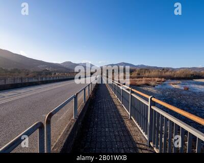 Fluchtpunkt auf der Brücke über den Fluss Magra in Lunigyana, in der Nähe von Aulla. Winterlandschaft. Nordtoskanisch. Stockfoto