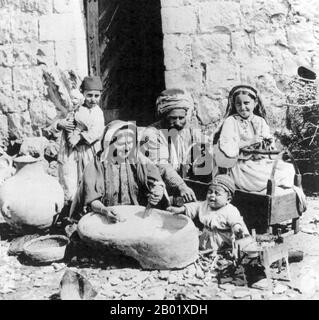 Palästina: Eine glückliche palästinensische Familie von Ramallah mit einem weinenden Kleinkind, Anfang des 20. Jahrhunderts. Palästina ist ein Name für die geografische Region zwischen dem Mittelmeer und dem Jordan. Die Region ist auch als das Land Israel, das Heilige Land und die Südlevante bekannt. 1832 wurde Palästina von Mohammed Alis Ägypten erobert, aber 1840 intervenierte Großbritannien und gab die Kontrolle über die Levante an die Osmanen zurück, als Gegenleistung für weitere Kapitulationen. Am Ende des 19. Jahrhunderts begann die zionistische Einwanderung und die Wiederbelebung der hebräischen Sprache. Stockfoto