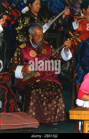 China: Ein Mann spielt einen Sanxian, das Naxi (Nakhi) Folk Orchestra, die Naxi-Orchesterhalle, Lijiang Old Town, Provinz Yunnan. Naxi-Musik ist 500 Jahre alt und hat mit ihrer Mischung aus literarischen Texten, poetischen Themen und musikalischen Stilen der Tang-, Song- und Yuan-Dynastien sowie einigen tibetischen Einflüssen einen eigenen, einzigartigen Stil und Züge entwickelt. Es gibt drei Hauptstile: Baisha, Dongjing und Huangjing, alle mit traditionellen chinesischen Instrumenten. Die Naxi oder Nakhi sind eine ethnische Gruppe, die am Fuße des Himalaya im Nordwesten der Provinz Yunnan lebt. Stockfoto