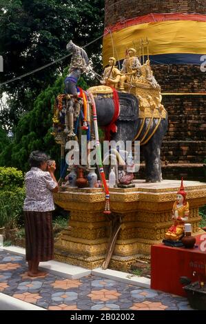 Thailand: Eine alte Dame betet in Ku Chang, einem Chedi, der über dem Grab von Blacky Purple, dem großen Kriegselefanten von Königin Chamathewi, Lamphun, im Norden Thailands gebaut wurde. Als Königin Chamadevi' großer Kriegselefant Blacky Purple starb, wurde er mit großer Ehre unter einem Chedi begraben, der noch immer in der Nähe des Bahnhofs Lamphun steht. Auch hier sind Denkmäler von Chamadevi schnellstem Pferd, ihrer Lieblingskatze und einem speziellen Hahn zu sehen, „der so laut und schrill krähte, dass er bis Lopburi deutlich zu hören war“. Das Monument von Blacky Purple, auch bekannt als Ku Chang, ist das eindrucksvollste dieser Monumente Stockfoto