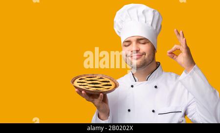 Freut Mich, Dass Die Baker Holding Pie Okay Über Den Gelben Hintergrund, Panorama, Gestikuliert Hat Stockfoto