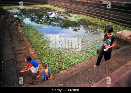 Thailand: Kinder spielen um einen der Tempeltanks, Prasat Mueang Tam, Provinz Buriram, Nordosten Thailands. Prasat hin Mueang Tam ist ein Khmer-Tempel im Khleang- und Baphuon-Stil, der aus dem späten 10. Und frühen 11. Jahrhundert stammt. Die Hauptgottheit war Shiva, obwohl Vishnu auch hier verehrt wurde. Prasat Mueang Tam wurde auf Befehl von König Jayavarman V. erbaut. Umgeben von einer hohen lateritalen Mauer, umfasst der Komplex prächtige Stufenbecken, die liebevoll restauriert und mit Lotusblüten gefüllt wurden. Stockfoto