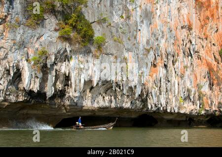 Thailand: Bootsführer neben der unterschnittenen Klippe, Ao Phang Nga (Phangnga Bay) Nationalpark, Provinz Phang Nga Stockfoto