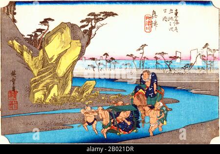 Japan: Station Seventeen: Quer the Okitsu River. Ukiyo-e-Holzschnitt aus der Serie „Three Stations of the Tôkaidô Road“ von Utagawa Hiroshige (1797-1858), um 1834. Okitsu: Blick in der Nähe der Mündung des Okitsu River, Blick auf das Meer, und zwei Sumo-Wrestler werden flussaufwärts getragen, einer auf einem Packpferd und der andere auf einem Kago. Diese flache Gegend ist bekannt für ihre schöne Aussicht auf den Pinienhain „Mihonomatsubara“, hervorgehoben durch die hübsche Meereskulisse. Stockfoto