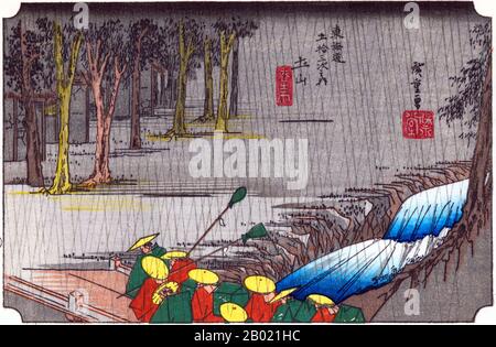 Japan: Station Neunundvierzig: Tsuchi-Yama, Spring Rain. Ukiyo-e-Holzschnitt aus der Serie „Three Stations of the Tôkaidô Road“ von Utagawa Hiroshige (1797-1858), um 1834. Tsuchi-yama: Der Kopf eines Daimyos, der einen Bach durch eine Brücke in Richtung Dorf überquert, versteckt in einem Baumhain, unter starkem Regen. Diese im Bergwald gelegene Station war bekannt für ihre reichlichen Frühlingsniederschläge. Bei starkem Regen überqueren die Vorhut einer Prozession eines Feudalherrn in Regenmänteln eine kleine Brücke, die einen sintflutartigen Bach überspannt. Stockfoto