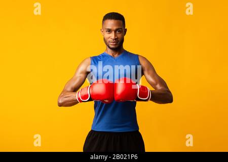 Gutaussehender Afro Sportsman bereit für den Kampf im Orange Studio Stockfoto