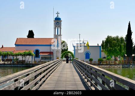 Porto Lagos, Griechenland - Juni 09, 2018: Unbekannter Priester und Besucher auf hölzernen Brücke zum Kloster Agios Nikolaos, Vistonida See Stockfoto