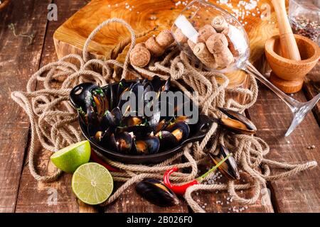 Gekochte Miesmuscheln in Kupfer Schale zum Kochen auf hölzernen Hintergrund close-up Stockfoto