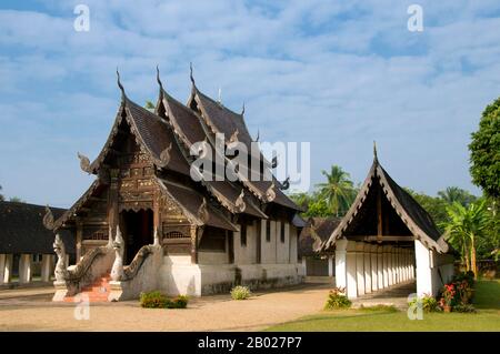 Thailand: Alter Viharn mit umliegendem Kloster, Wat Ton Kwen, Chiang Mai. Wat Ton Kwen, früher als Wat Inthrawat bekannt, bedeutet „Tempel der Zuckerpalmen“ in kham muang oder Nordthailand. Der rustikale Tempel, der sich in einem kleinen Dorf inmitten von grünen Reisfeldern befindet, ist von hohen und eleganten Zuckerpalmen umgeben. Das zu Beginn der Regierungszeit von Chao Kawilorot (R. 1856–1870) im Jahr 1856 erbaute Wat Ton Kwen gehört zu den besten und reinsten Beispielen, die die traditionelle Holzarchitektur des LAN Na Tempels aus dem 19. Jahrhundert erhalten hat. Stockfoto