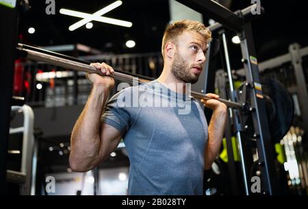 Mann mit Krafttrainingsausrüstung im Sportclub Stockfoto