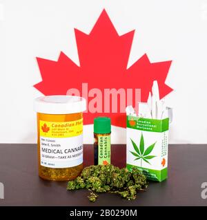 Cannabis in Kanada. Medizinisches Cannabis, Cannabisöl, Knospen und ein Paket Cannabiszigaretten auf einem Tisch, hinter dem ein kanadisches Ahorn-Blatt steht. Stockfoto