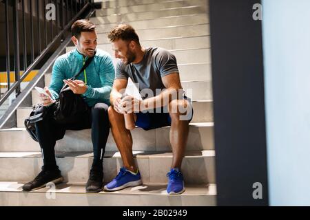 Gutaussehende Fit Männer Freunde sprechen, lächeln nach dem Training im Fitnessstudio Stockfoto