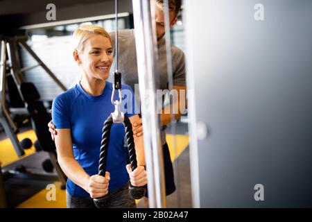 Fröhliche Frau, die mit ihrem persönlichen Trainer im Fitnessstudio trainiert Stockfoto