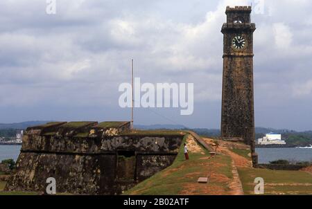 Sri Lanka: Mondbastion und Uhrturm, Galle. Galle war jahrhundertelang der Haupthafen Sri Lankas, eine Position, die während der portugiesischen und niederländischen Kolonialherrschaft gestärkt wurde. Galle verlor erst im späten 19. Jahrhundert seinen Vorsprung, als die Briten den Hafen von Colombo zum Haupthafen der Insel erweiterten. Die früheste urkundliche Erwähnung von Galle stammt vom großen arabischen Reisenden Ibn Battuta, der Mitte des 14. Jahrhunderts den Hafen besuchte, den er Qali nennt. Stockfoto