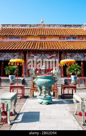 Vietnam: Thế Miếu (der Mieu) Ahnentempel, die Kaiserstadt, die Zitadelle, Hue. Der Thế Miếu, auch Thế Tổ Miếu genannt, ist ein Ahnentempel und wurde 1822–1823 auf Befehl von Kaiser Minh Mạng errichtet. Er ehrt die Kaiser der Nguyễn-Dynastie. Neun dynastische Urnen (Vietnamesisch cửu đỉnh) vor dem Thế Miếu wurden ebenfalls 1822 gegossen und den ersten neun Kaisern der Nguyen gewidmet. Kaiser Gia Long ordnete 1805 den Bau der Zitadelle von Hue an. Der riesige Komplex wurde nach den Vorstellungen von Fengshui oder chinesischer Geomanz gebaut. Stockfoto