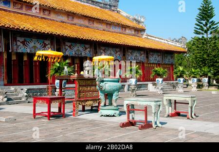 Vietnam: Thế Miếu (der Mieu) Ahnentempel, die Kaiserstadt, die Zitadelle, Hue. Der Thế Miếu, auch Thế Tổ Miếu genannt, ist ein Ahnentempel und wurde 1822–1823 auf Befehl von Kaiser Minh Mạng errichtet. Er ehrt die Kaiser der Nguyễn-Dynastie. Neun dynastische Urnen (Vietnamesisch cửu đỉnh) vor dem Thế Miếu wurden ebenfalls 1822 gegossen und den ersten neun Kaisern der Nguyen gewidmet. Kaiser Gia Long ordnete 1805 den Bau der Zitadelle von Hue an. Der riesige Komplex wurde nach den Vorstellungen von Fengshui oder chinesischer Geomanz gebaut. Stockfoto