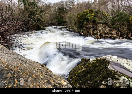 Schnell fließendes Wasser passiert Felsen im River Owentocker bei Ardara, County Donegal, Irland Stockfoto