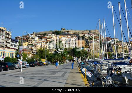 Kavala, Griechenland - 17. September 2015: Unidentifizierte Menschen an der Promenade entlang des Hafengeländes mit Segelschiffen und Festung oben Stockfoto