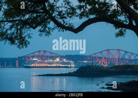 Ein Kreuzfahrtschiff zündete nachts unter der Forth Rail Bridge in der Nähe von Edinburgh Scotland an. Stockfoto