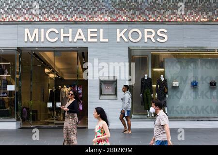 Indische Reisetouren, die an einem Luxusmarkengeschäft von Michael Kors entlang der Orchard Road, Singapur, vorbeilaufen. Stockfoto