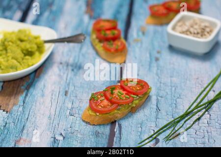 Sandwiches mit offenem Gesicht. Offenes Sandwich und ein paar Schnittlauch grüne Stiele daneben liegen im Vordergrund auf blauem rustikalem Hintergrund. Stockfoto