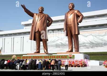 Das Grand Monument auf dem Mansu-Hügel (Mansudae) ist ein Denkmalkomplex in Pjöngjang, Nordkorea. Der zentrale Teil des Denkmals sind zwei 22 Meter hohe Bronzestatuen der nordkoreanischen Führer Kim Il-sung und Kim Jong-il. Hinter den Statuen befindet sich eine Wand des koreanischen Revolution Museum Gebäudes, die ein Mosaikgemälde zeigt, das eine Szene vom Berg Paektu zeigt, die als der heilige Berg der Revolution angesehen wird. Das Denkmal wurde im April 1972 errichtet und zeigt dann nur Kim Il-sung. Nach dem Tod von Kim Jong-il wurde eine ähnliche Statue von ihm auf der linken Seite von Kim Il-sung aufgestellt. Stockfoto