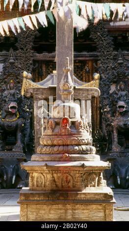 Rudravarna Mahavihara, oder Oku Bahal, wurde Mitte des 17. Jahrhunderts erbaut. Der Tempel befindet sich um einen Innenhof, der mit Chaitya- und Metallfiguren aller Art und Größen überströmt ist. Es gibt massive Garudas, Elefanten, Pfauen, Figuren betender Anbeter und eine Statue von Juddha Shamsher Rana, die dem Tempel nach dem Erdbeben von 1934 großzügige Wiederherstellungshilfen gewährt haben. In den Ecken des mit Öllampengeländern gesäumten Innenhofes befinden sich Bronzefiguren des boshaften affengottes Hanuman, die ihm beim Verzehr eines Kürbisses, einer Banane und etwas zeigen, das wie ein aussieht Stockfoto