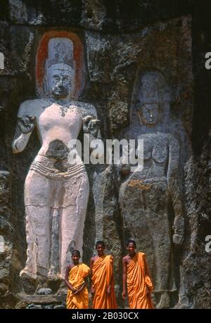 Die abgelegene alte buddhistische Stätte Bururuvagala (was 'Stone Buddha-Bilder' auf Singhalesisch bedeutet) stammt aus dem 10. Jahrhundert, als der Mahayana-Buddhismus Teile Sri Lankas beherrschte. In die Felswand gehauen ist eine riesige 16 m hohe Buddha-Figur, auf jeder Seite drei kleinere Figuren. Avalokiteśvara ('Herr, der hinunterblickt') ist ein Bodhisattva, der das Mitleid aller Buddhas verkörpert. In verschiedenen Kulturen als männlich oder weiblich dargestellt, ist Avalokiteśvara einer der am weitesten verehrten Bodhisattvas im Mainstream-Mahayana-Buddhismus sowie inoffiziell im Theravada-Buddhismus. Stockfoto