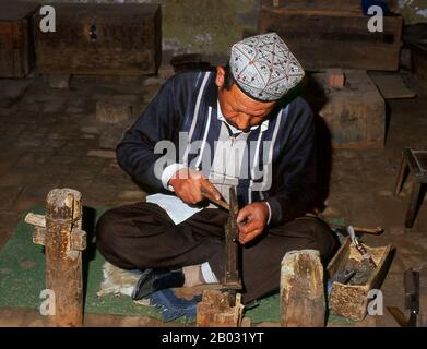 Die kleine von Uiguren dominierte Oase Yengisar (Yingjisha) ist in der gesamten westchinesischen Provinz Xinjiang für die Herstellung von handgefertigten Messern bekannt. Die Kleine Messerfabrik (Pichak Chilik Karakhana/Xiadaochang) beschäftigt erfahrene Handwerker vor Ort, die feine Messer mit eingelegten Griffen herstellen. Fast jeder uigurische Mann trägt ein Messer, sowohl als Zeichen der Manschaft als auch für den utilitareren Zweck, Melonen aufzuschneiden, und die wertvollsten (und teuersten) stammen aus Yengisar. Stockfoto